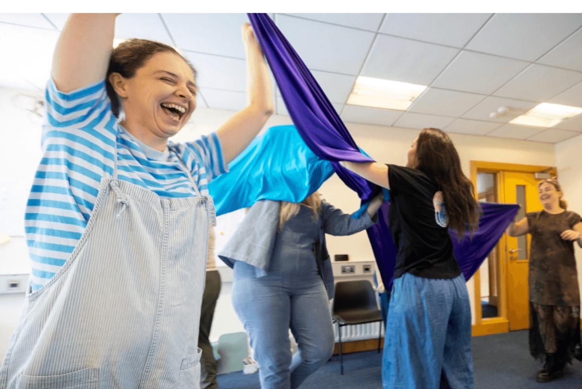 group of women doing a dance with coloured material