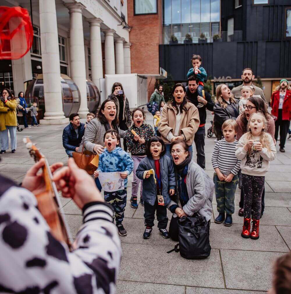 a group of children watching a person playing a guitar outside