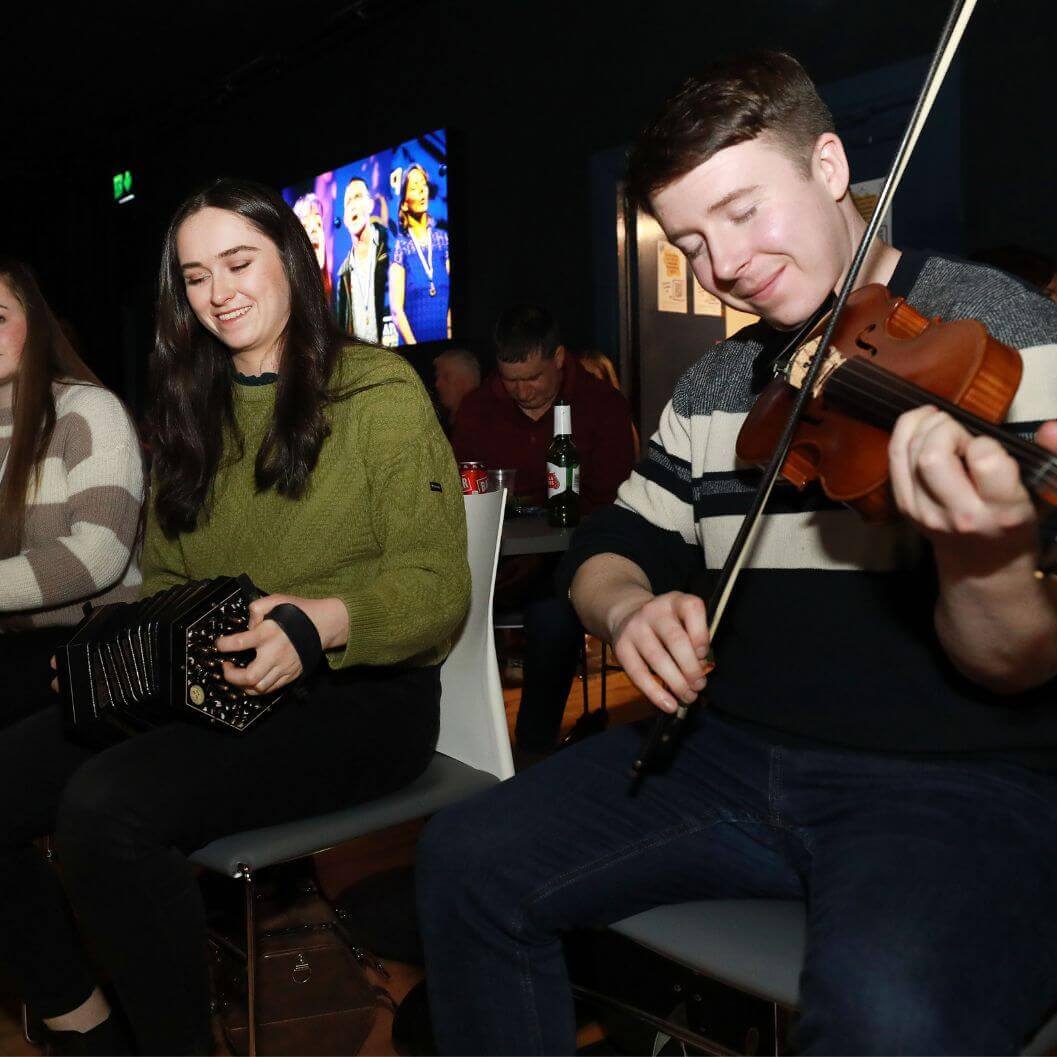 a young woman and man one playing an accordion and the other the fiddle