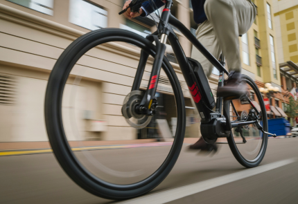 Image shows the closeup of an electric bike being ridden on the road by a man