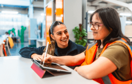 Support worker helping a young visually-impaired individual learn how to use a tablet