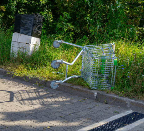 Abandoned shopping trolley upturned on a grassy sidebank