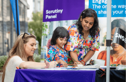 Young mum and daughter colouring with an SNG employee at a community event