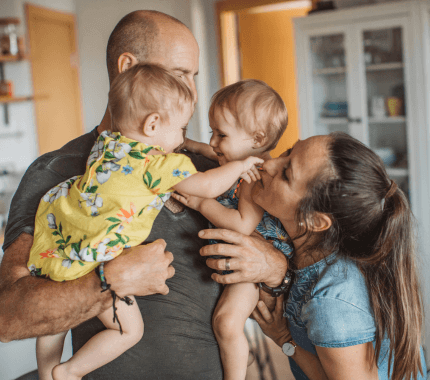 Family with twins all share a hug together