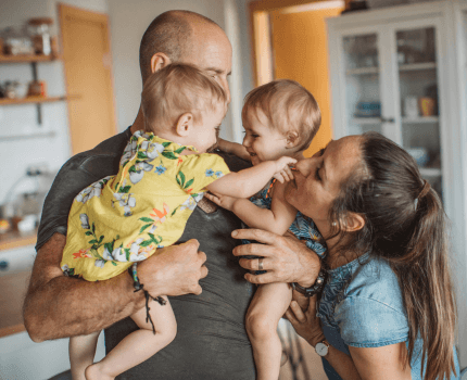 Family having a group hug whilst baby twins play with their parents