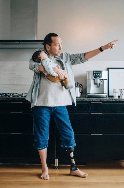 A customer stands holding their newborn baby with a prosthetic leg