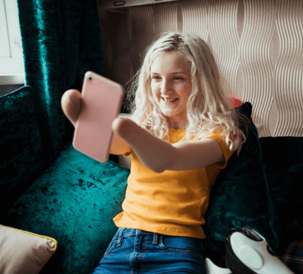 An individual with a double amputation holds out their phone whilst smiling