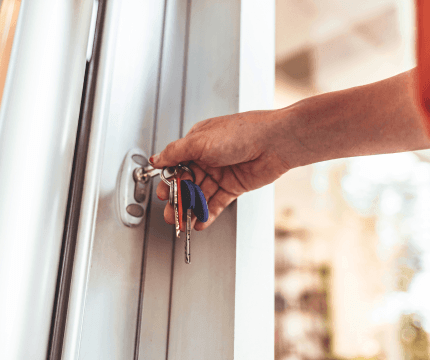 Close up of a hand and arm opening a door with a collection of keys