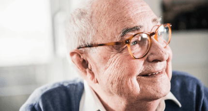 Close up of older customer smiling into the distance whilst wearing glasses
