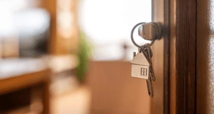 Door ajar with a silver house keyring in the lock