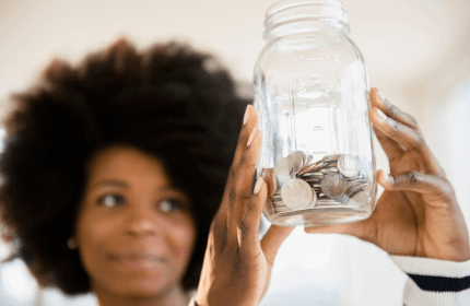 Individual holding up a glass savings jar full of change