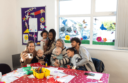 Group of mixed-race individuals and children smiling for a community group picture
