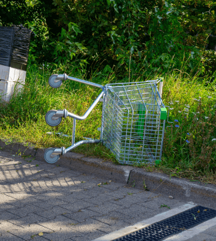 Abandoned shopping trolley upturned on a grassy side-bank