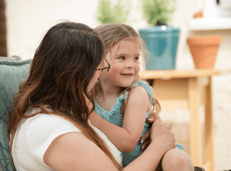 Customer smiling at their child whilst sitting outside