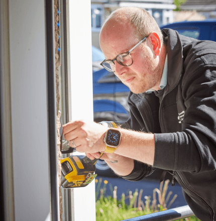 SNG tradesman fixing a customer's door with a drill