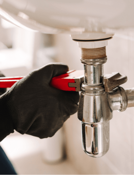 Plumber with gloved hands fixing a leaky sink