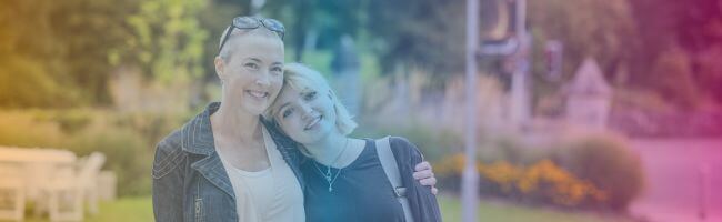 Parent hugs young person and smiles to camera