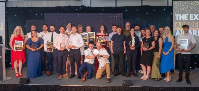 Apprentice award winners hold their awards and smile to camera 