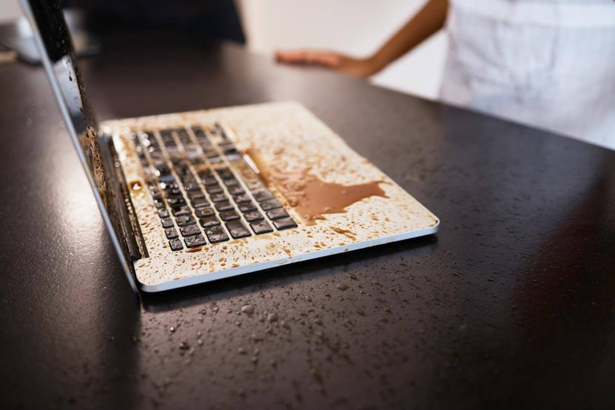 Liquid spilled across a laptop keyboard on a desk.