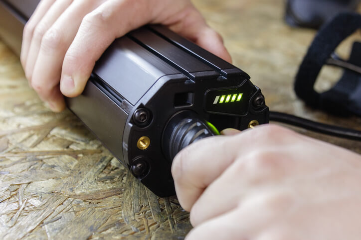 A person’s hands connecting a cable to a black lithium-ion rechargeable battery pack.