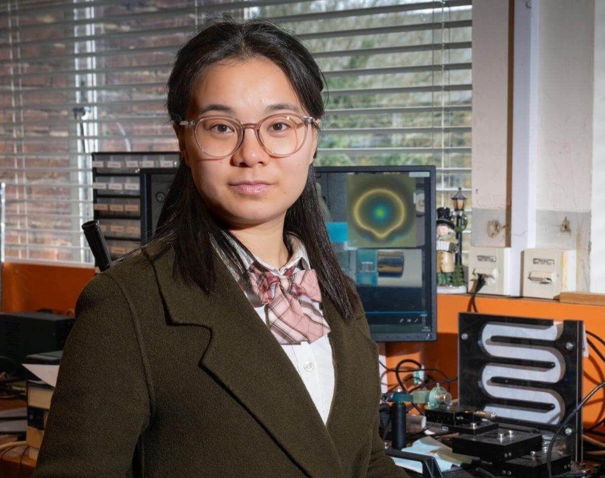 Chaolu standing at a laboratory workbench with a laptop and scientific equipment in a research lab.