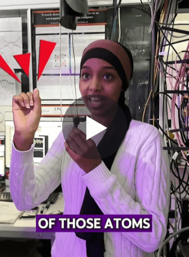 YouTube Short thumbnail showing postdoctoral researcher Sahra in Sussex’s quantum lab. A play button is centred on the image, with red arrows and the caption “OF THOSE ATOMS” at the bottom.