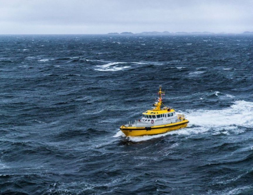 Yellow coastguard boat navigating through rough sea waves.