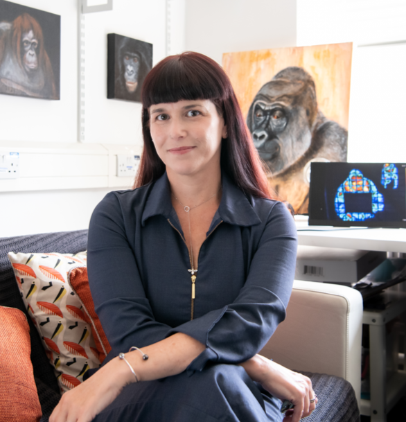 Professor Gillian Forrester seated in her office, with gorilla artwork and a computer displaying thermal images in the background.