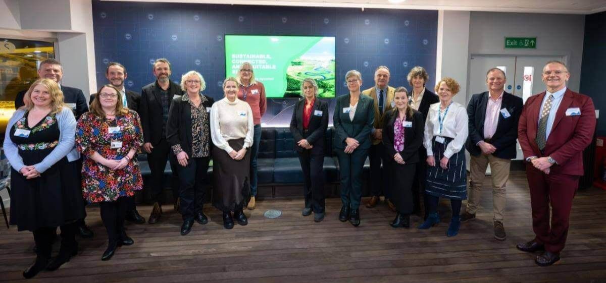Group photo of university leaders and local partner representatives at the launch of the Civic University Agreement, standing in front of a screen that reads “Sustainable, connected and equitable Sussex."