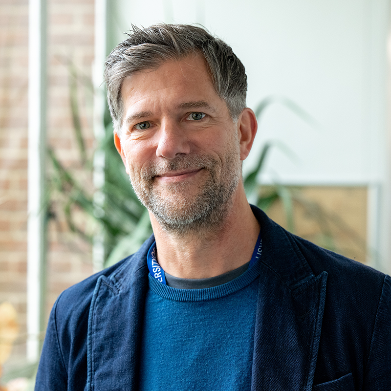 Professor Ulrich Rass, smiling at the camera, wearing a blue jumper and jacket.